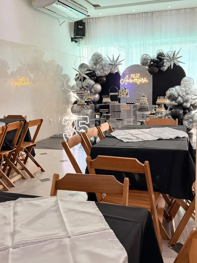 Salão do Espaço Big House decorado para festa de 15 anos com painel e balões prata e preto