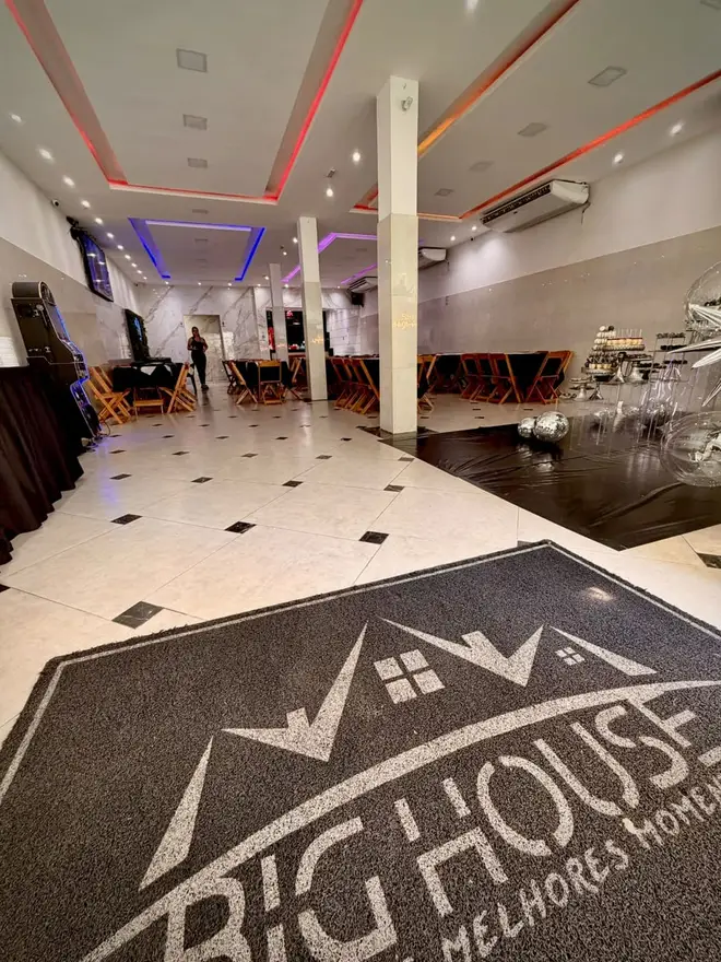 Entrada do Espaço Big House na Penha com tapete personalizado Big House e salão iluminado ao fundo