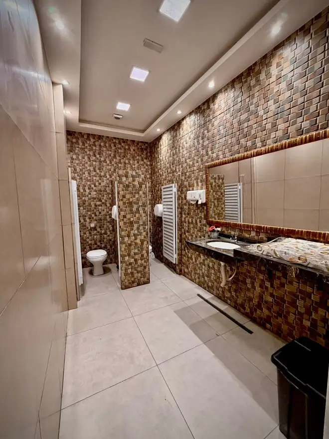Banheiro do Espaço Big House com revestimento em mosaico, espelho amplo e bancada de pia